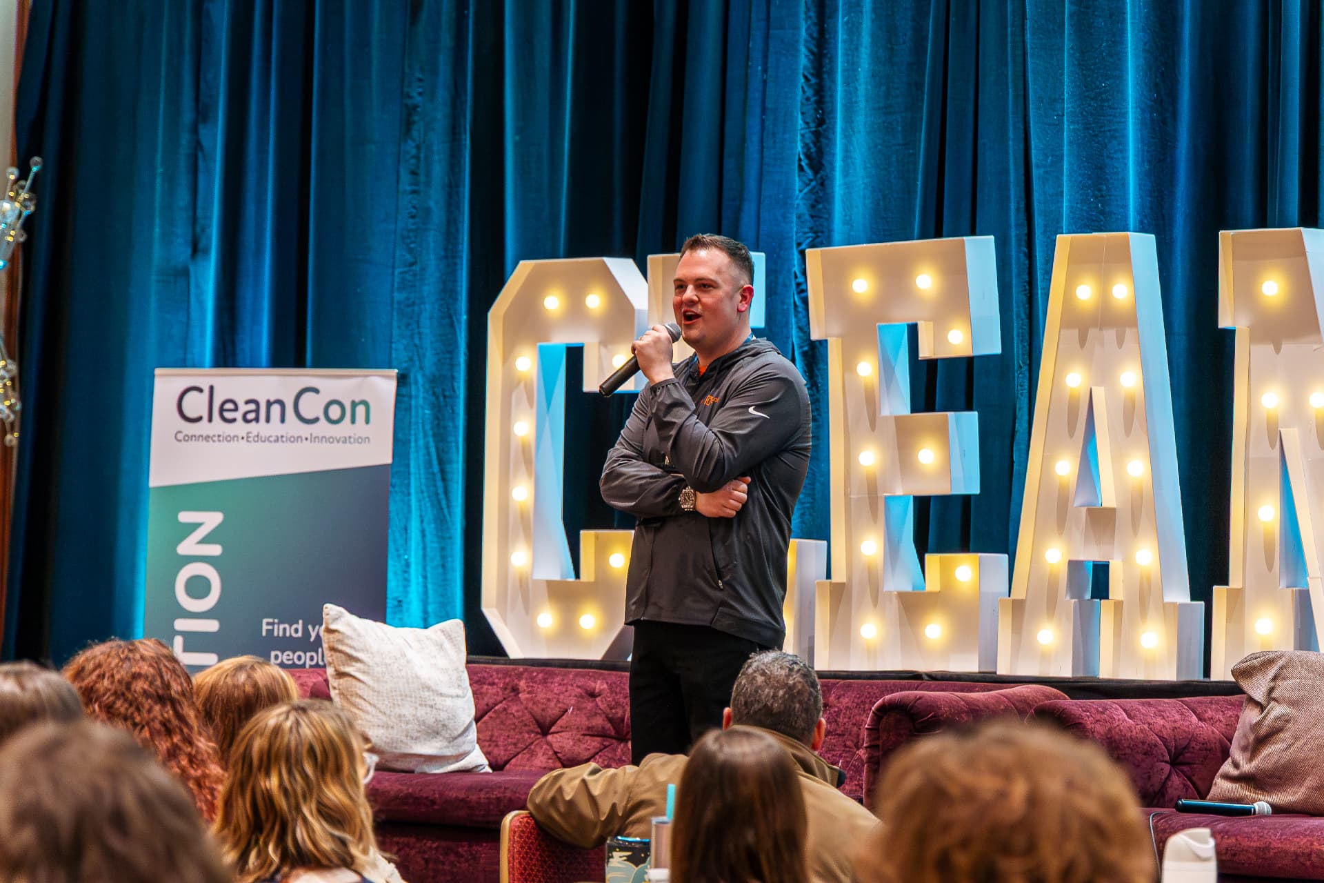 Drew Larison speaking on the CleanCon stage in front of illuminated CLEAN letters